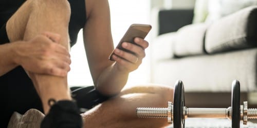 Mann mit Smartphone zur Darstellung des Online Fitness-Coachings